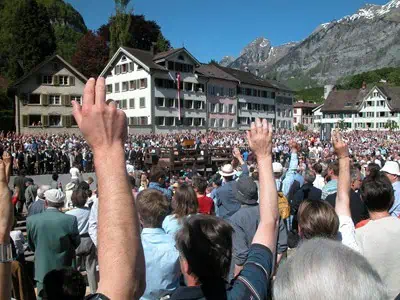 Bürgerinnen und Bürger in Glarus heben die Hand zum Abstimmen bei der Landsgemeinde, einer traditionellen Versammlung unter freiem Himmel in der Schweiz.